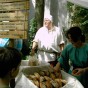 Foto: Ein mittelalterlich gewandeter Kollege steht vor einem Tisch mit Brot. Er gehört zur Mittelalterküche. Seitlich sieht man eine hölzerne Verkaufstafel