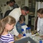 Kinder betrachten verschiedene Ledersorten durch ein Mikroskop.