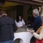 Blick auf den historischen Verkaufsstand des mittelalterlichen Gerichts. Davor stehen Besucher und nehmen gefüllte Teller in Empfang, dahinter stehen zwei mittelalterlich gewandete Frauen und bieten Suppe und Bier an.